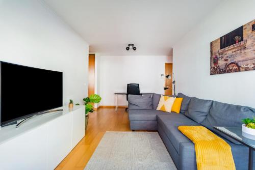 uma sala de estar com um sofá azul e uma televisão de ecrã plano em Olaias Flat (with Free Parking) em Lisboa