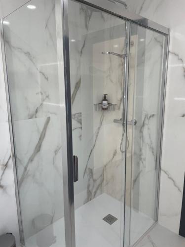 La salle de bains est pourvue d'une douche avec une porte en verre. dans l'établissement Soho Moraleja II duplex, à Alcobendas