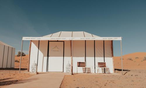 a tent with a table and chairs in the desert at Dihya desert camp in Merzouga