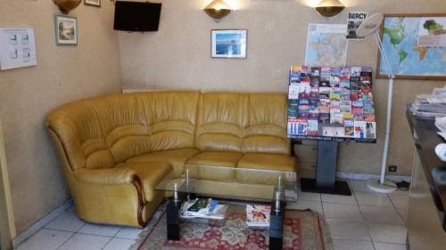 a leather couch in a living room with a table at Hotel Paris Bercy in Paris