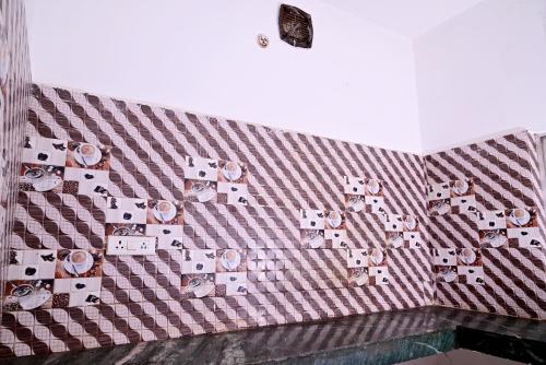 a tiled wall with pictures on it at Shivay Guest house in Jasidih