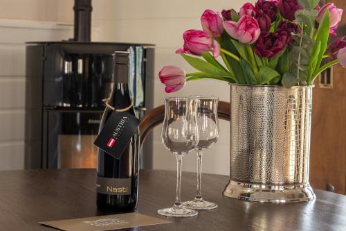 una botella de vino y un jarrón de tulipanes rosas en Londons Cottage en Hilversum