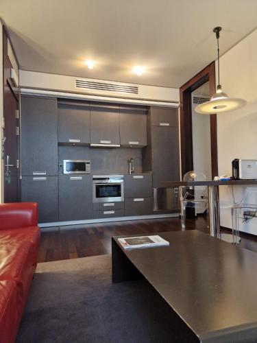 a living room with a red couch and a kitchen at Hotel Maroa Vigo in Vigo