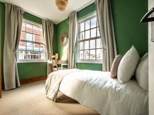 a green bedroom with a bed and two windows at Pass the Keys Modern central flat with character features in Exeter