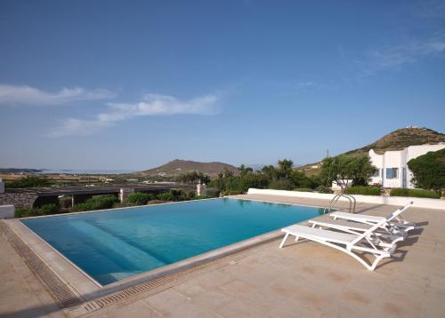 een zwembad met 2 ligstoelen en een huis bij Amelie Villa with pool and amazing sea views, Paros in Márpissa