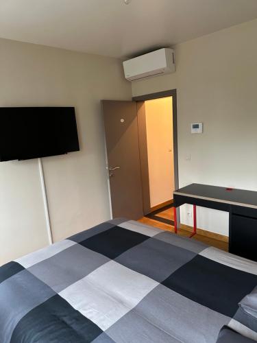 a room with a bed and a desk and a television at Chambre hôte in Brussels