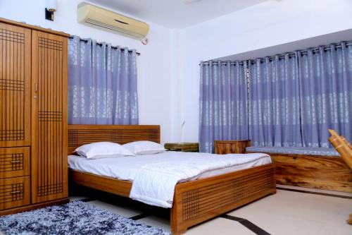 a bedroom with a bed and a large window at Nirapod Holiday Home in Sylhet