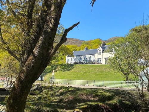 a large white house on a hill with a fence at The Old Schoolhouse in Morar