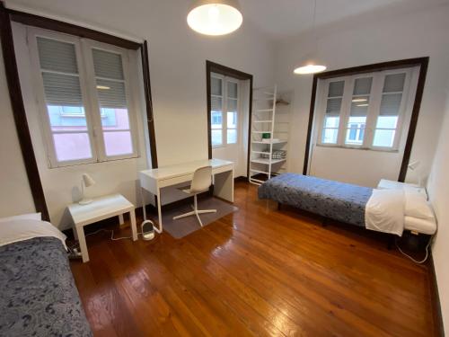 um quarto com 2 camas, uma secretária e uma mesa em BREINER 28 no Porto