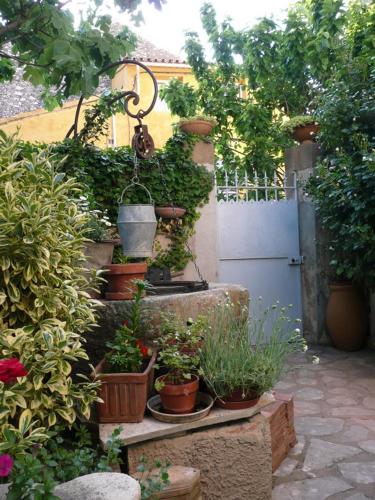 un jardin avec des plantes en pot sur le côté d'un mur dans l'établissement Au Puits de la Fontaine, à Tavernes