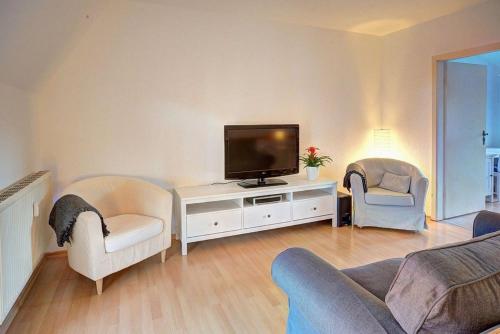 ein Wohnzimmer mit einem Flachbild-TV und Stühlen in der Unterkunft Traumfänger in Wismar