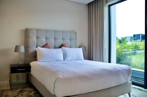 um quarto com uma cama grande e uma janela grande em Outstanding 2BR Sandton with a View em Joanesburgo