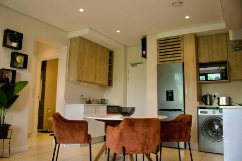 uma cozinha com uma mesa e cadeiras numa cozinha em Outstanding 2BR Sandton with a View em Joanesburgo