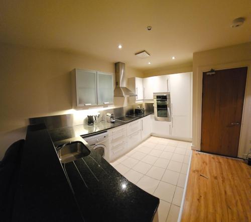 a kitchen with white cabinets and a black counter top at Penthouse Apartment in Kilkenny