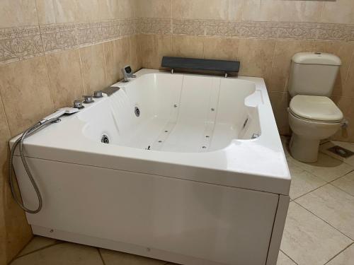 a white bath tub in a bathroom with a toilet at Charming Villa in Sheikh Zayed