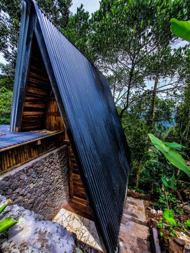 姆杜克的住宿－Munduk Umah Cabin，一座有黑色屋顶的建筑,有树木