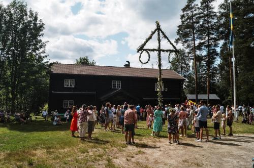 a crowd of people standing in front of a black barn at Vikinggård Cottages in Höljes