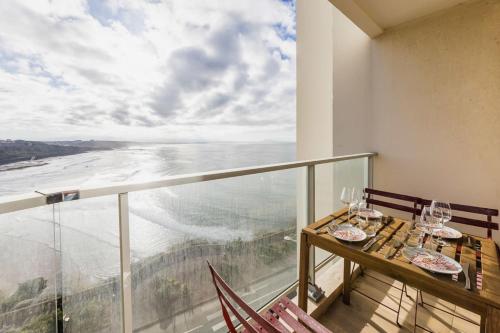 un balcon avec une table et des chaises et une vue sur l'océan dans l'établissement BLUE UHAINA KEYWEEK Sea view apartment Biarritz downtown, à Biarritz