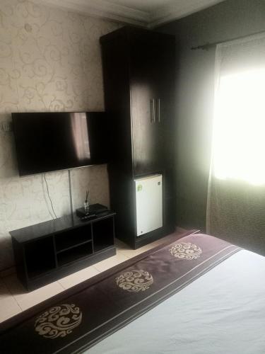 een kleine kamer met een bed en een televisie bij CRYSTAL SUITES in Akure