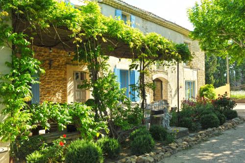 dom z kupą roślin przed nim w obiekcie Le Mas Terre des Anges w mieście Sarrians