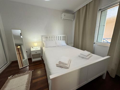 Un dormitorio con una cama blanca con toallas. en Traditional Seaview Maisonette en Saronida