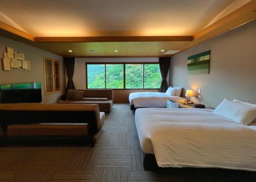 Habitación de hotel con 2 camas y sofá en Yuze Hotel en Kazuno