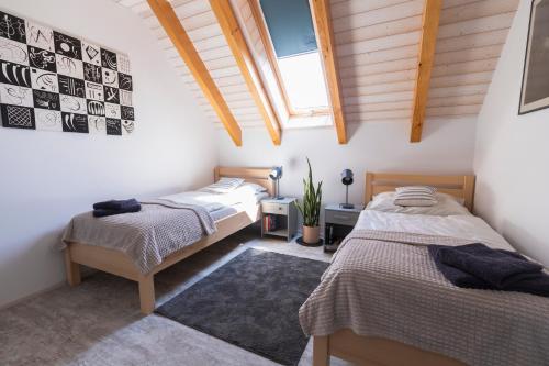 two beds in a room with wooden ceilings at Apartmán Sychrova in Žďár nad Sázavou