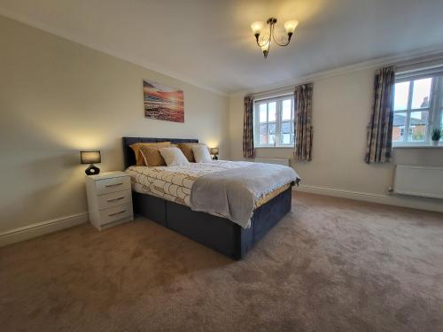 a bedroom with a large bed and two windows at Rare Contemporary 5 Bed London Home 7min - Station in Surbiton