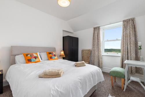 a bedroom with a large white bed and a window at Penalun House - Beautiful Sea Views in Penally