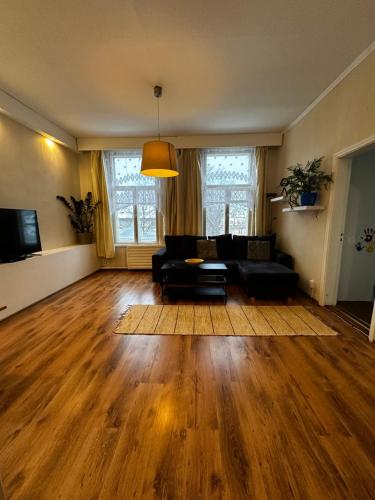 a living room with a black couch and wooden floors at Family Apartment near Kadriorg Swan Pond in Tallinn