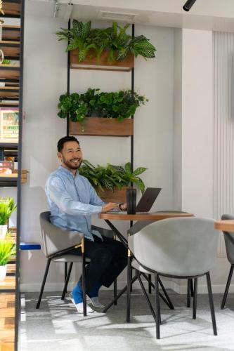 a man sitting at a table with a laptop at Aiva Hostel in Bishkek