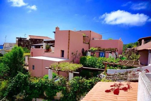 een roze huis met een tuin ervoor bij Villetta Costanza, Salina Isole Eolie in Rinella