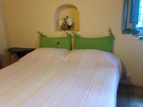 een slaapkamer met een wit bed met een groen hoofdeinde bij Villetta Costanza, Salina Isole Eolie in Rinella