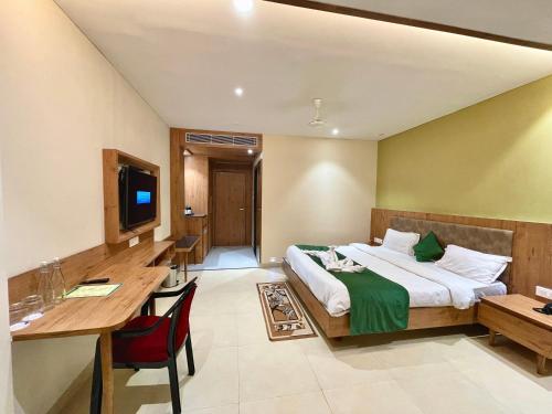 Habitación de hotel con cama, escritorio y TV. en Hotel ROCKBAY, Puri Swimming-pool, near-sea-beach-and-temple fully-air-conditioned-hotel with-lift-and-parking-facility en Puri