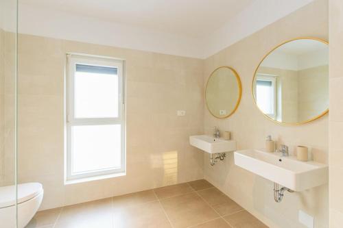 een witte badkamer met 2 wastafels en een spiegel bij Villa Impression by Istrialux in Ližnjan