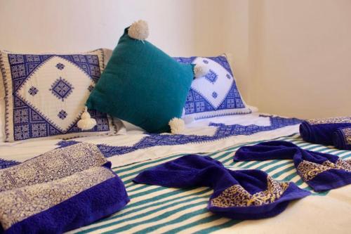 a bed with blue and white blankets and pillows at TRAVEL SURF NATURE in Tamraght Ouzdar