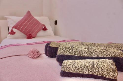 a bedroom with two beds with pink sheets and pillows at TRAVEL SURF NATURE in Tamraght Ouzdar