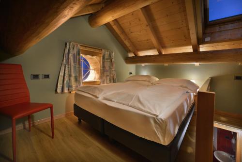 ein Schlafzimmer mit einem großen Bett und einem roten Stuhl in der Unterkunft Cronox Mini Apartments in Livigno