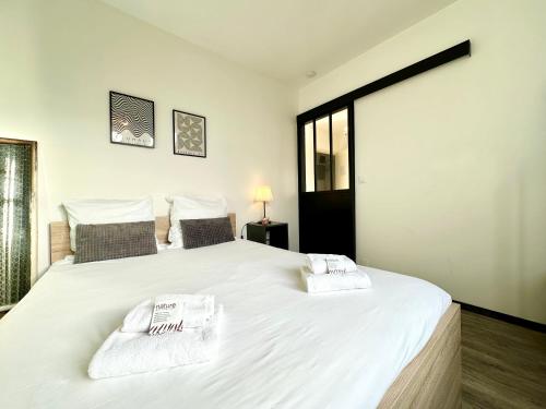 1 dormitorio con 1 cama blanca grande y toallas. en LE SAINT ROCH - Hyper Centre, en Mont-de-Marsan
