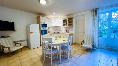 une cuisine avec une table, des chaises et un réfrigérateur dans l'établissement Villa en plein centre du village, de plain pied et rénovée en 2008, à Saint-Martin-de-Ré
