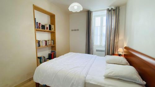 ein Schlafzimmer mit einem weißen Bett und einem Bücherregal in der Unterkunft Villa en plein centre du village, de plain pied et rénovée en 2008 in Saint-Martin-de-Ré