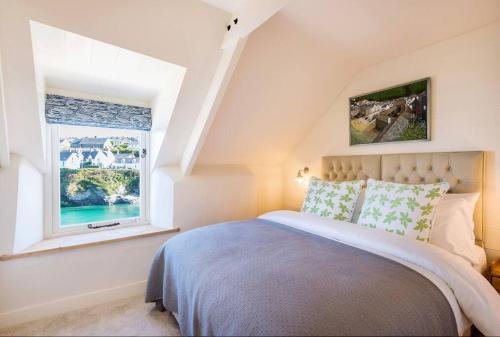 a bedroom with a bed and a window at White House, Port Isaac Bay Holidays in Port Isaac