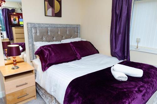 a bedroom with a large bed with purple sheets at 2ndHomeStays-West Bromwich- A Charming 2-Bedroom Maisonette in West-Midlands, Suitable for long Stay Contractors-Families-Group of Friends on Holiday, 10 mins to J1 M5 and 24 mins to Birmingham in West Bromwich