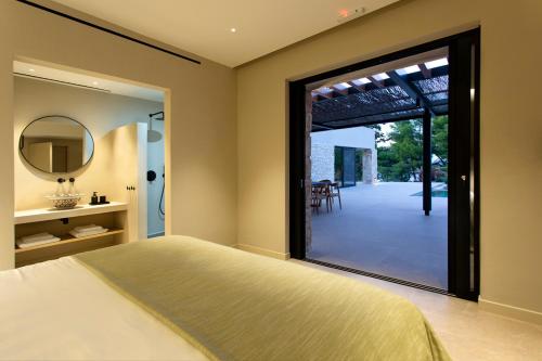 - une chambre avec un lit et une porte coulissante en verre dans l'établissement Theros Estate, à Amphilochie