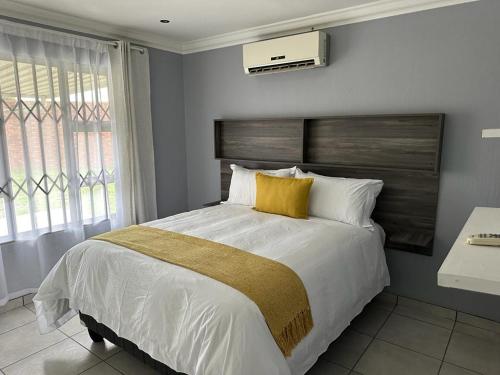 een slaapkamer met een groot bed met een geel kussen bij Beautiful 2 bedroom apartment In Richard's bay in Richards Bay