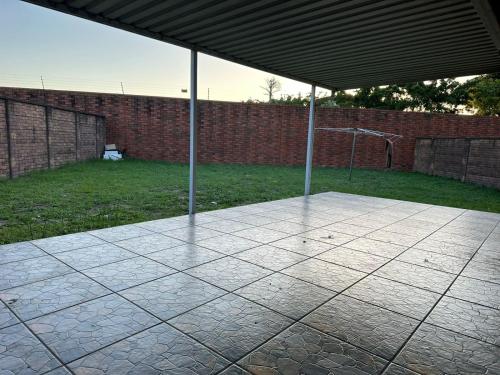 a patio with a covering and a brick wall and grass at Beautiful 2 bedroom apartment In Richard's bay in Richards Bay