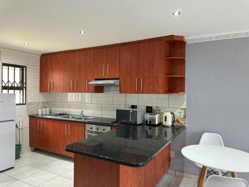 a kitchen with wooden cabinets and a black counter top at Beautiful 2 bedroom apartment In Richard's bay in Richards Bay