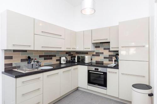 a white kitchen with white cabinets and appliances at Bournecoast: Patio Garden - Parking - WIFI -FM8455 in Bournemouth