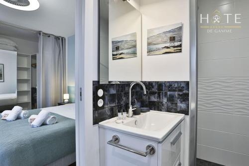 een badkamer met een wastafel, een bed en een spiegel bij Élégante maison avec piscine in Saint-Vincent-sur-Jard