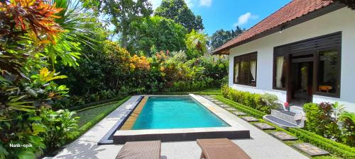 - une piscine dans un jardin à côté d'une maison dans l'établissement Sari Kembang villa ubud, à Ubud